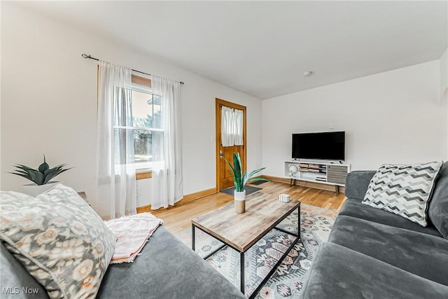 living area featuring baseboards and light wood finished floors