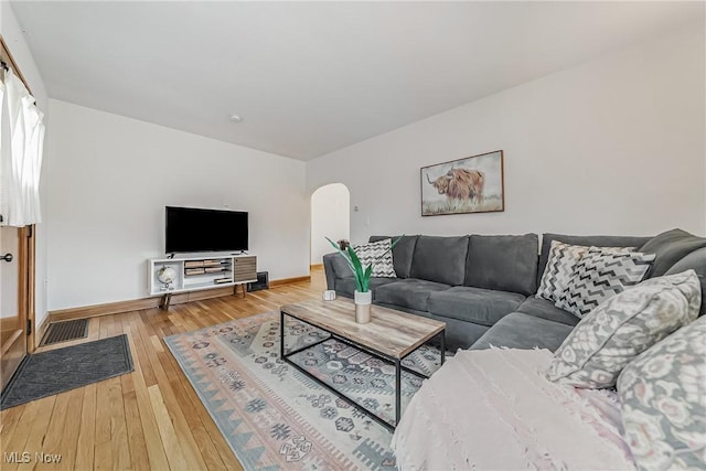 living area featuring baseboards, visible vents, arched walkways, and hardwood / wood-style floors