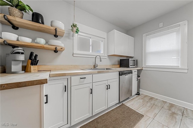 kitchen with light tile patterned floors, stainless steel appliances, open shelves, a sink, and butcher block countertops