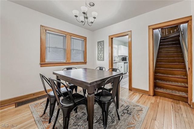 dining space with a chandelier, visible vents, baseboards, stairs, and light wood-type flooring