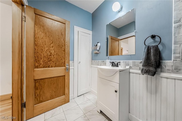 bathroom with marble finish floor, wainscoting, and vanity