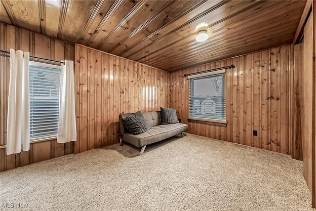 sitting room with carpet floors, a wealth of natural light, wood ceiling, and wooden walls