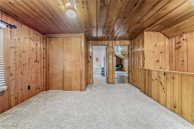 interior space with carpet floors, wood ceiling, and wooden walls