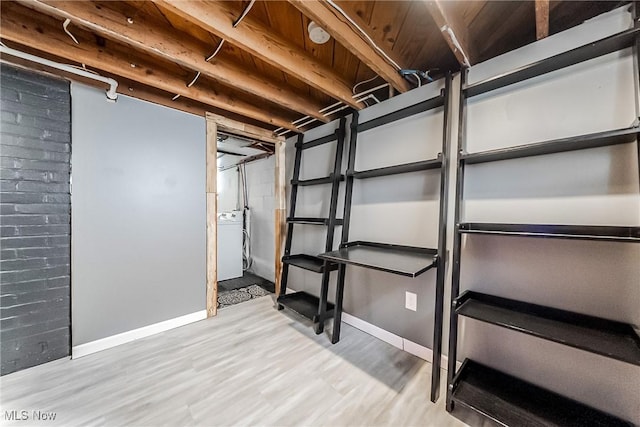 unfinished basement with washer / dryer, baseboards, and wood finished floors