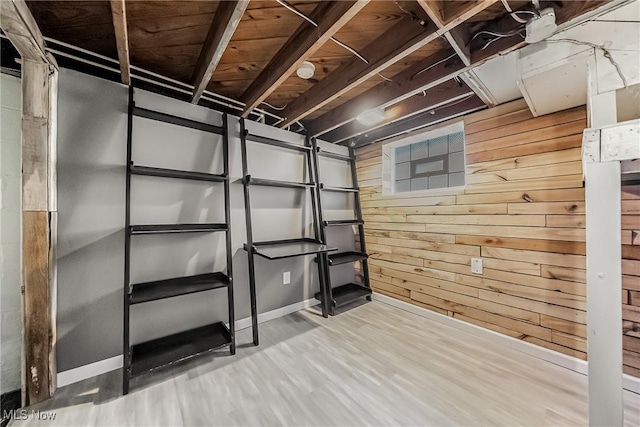 unfinished basement featuring wooden walls and wood finished floors