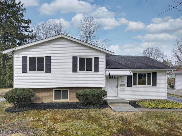 split level home with a shingled roof and brick siding