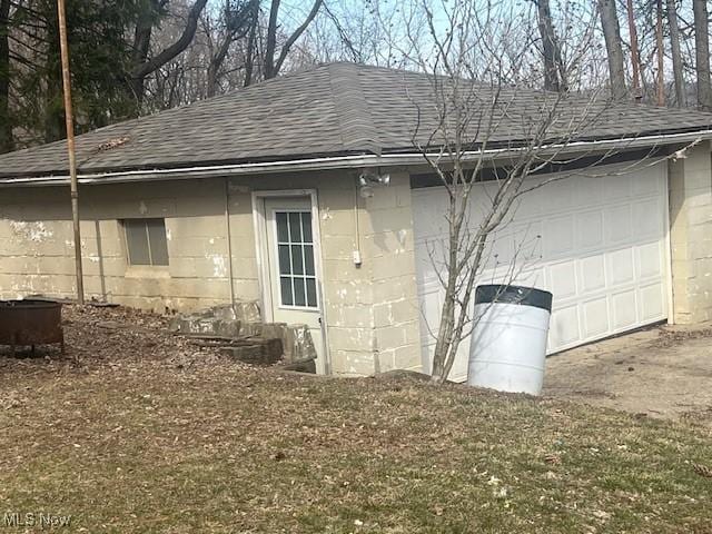 exterior space with a shingled roof and concrete block siding