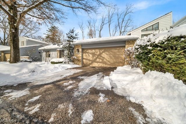 view of snowy exterior with a garage and driveway