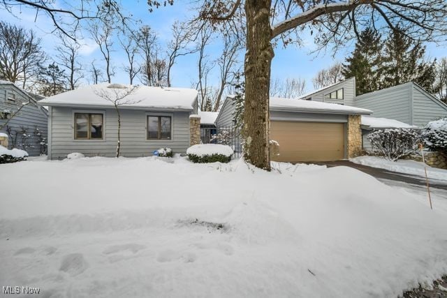 snow covered rear of property featuring an attached garage