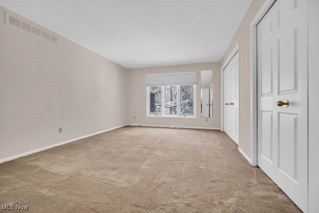 carpeted spare room featuring visible vents and baseboards