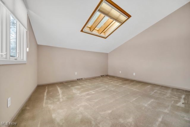 bonus room featuring lofted ceiling with skylight, carpet, visible vents, and baseboards