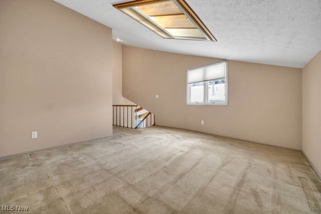 unfurnished room featuring lofted ceiling, a textured ceiling, and carpet