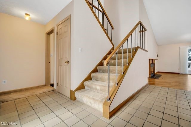 stairs featuring high vaulted ceiling, baseboards, and tile patterned floors