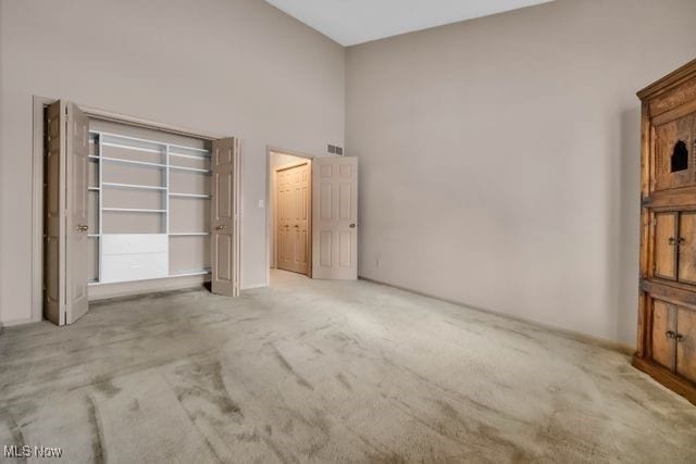 carpeted spare room with a high ceiling and visible vents