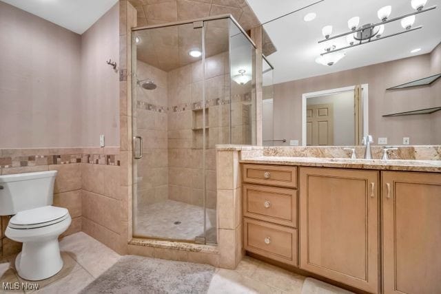 bathroom featuring toilet, a shower stall, vanity, and tile patterned floors