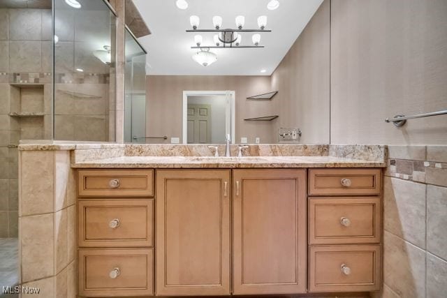 bathroom with tiled shower, vanity, and tile walls