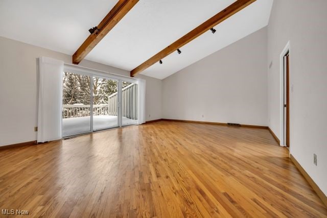 additional living space featuring light wood-style floors, vaulted ceiling with beams, and baseboards