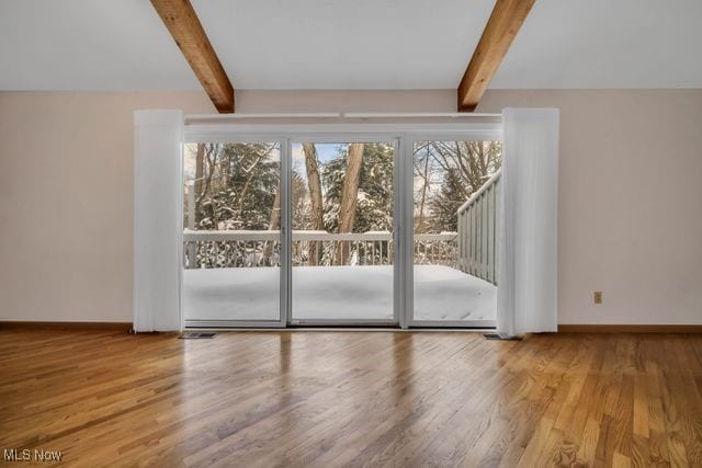 entryway featuring plenty of natural light, beamed ceiling, baseboards, and wood finished floors