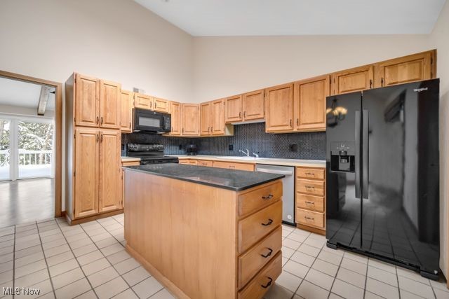 kitchen featuring a center island, light tile patterned floors, tasteful backsplash, a sink, and black appliances