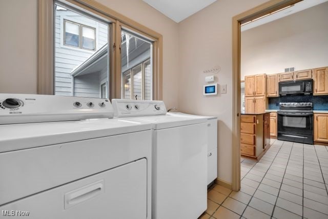 clothes washing area with laundry area, light tile patterned floors, and washing machine and clothes dryer