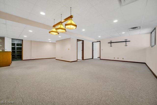 empty room featuring a drop ceiling, recessed lighting, light colored carpet, visible vents, and baseboards