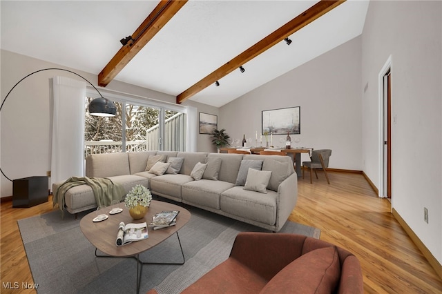 living area featuring high vaulted ceiling, light wood-style flooring, baseboards, and beam ceiling