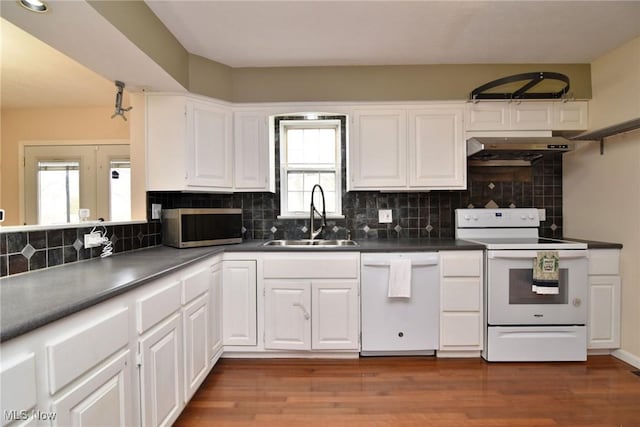 kitchen with white appliances, decorative backsplash, white cabinets, under cabinet range hood, and a sink