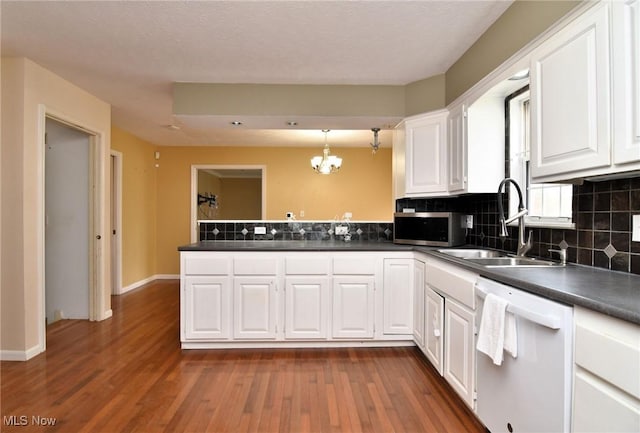 kitchen featuring a peninsula, a sink, white cabinetry, dishwasher, and stainless steel microwave