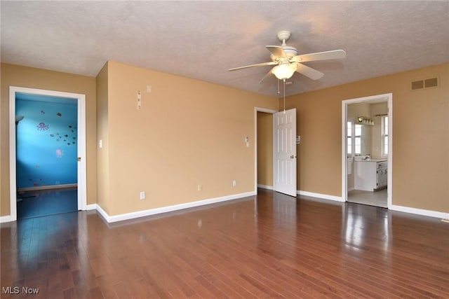 spare room with a textured ceiling, wood finished floors, a ceiling fan, visible vents, and baseboards