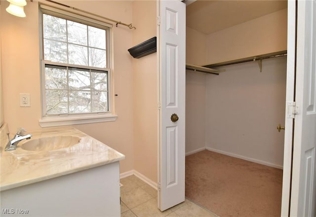 interior space with a spacious closet, vanity, baseboards, and tile patterned floors