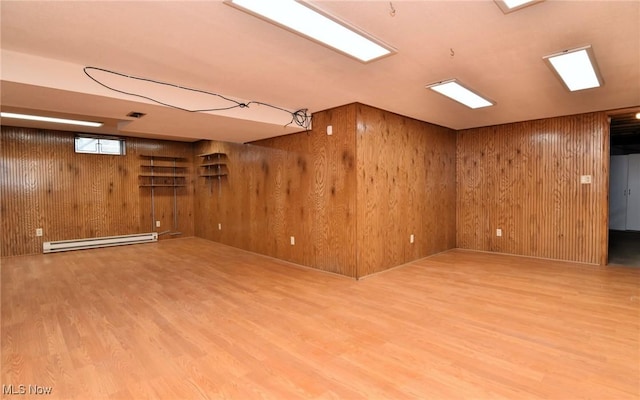 basement featuring a baseboard heating unit, wood finished floors, and wooden walls