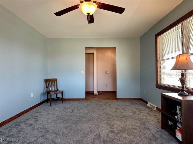 empty room featuring a ceiling fan, visible vents, baseboards, and carpet flooring