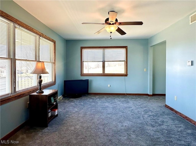 carpeted spare room with ceiling fan, visible vents, baseboards, and a wealth of natural light