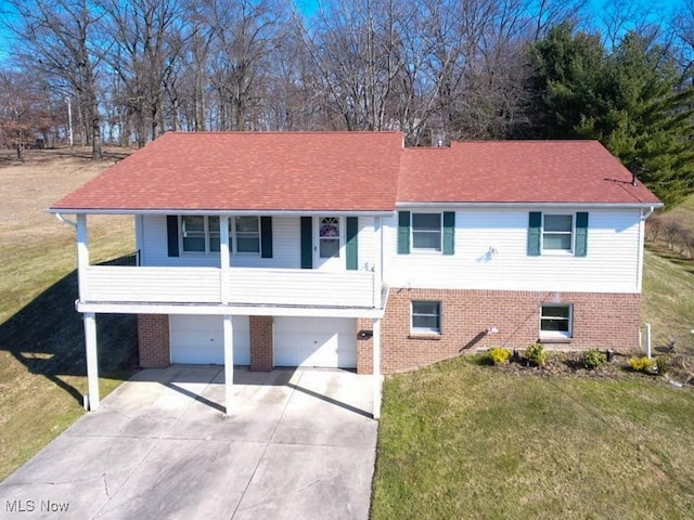 split foyer home featuring brick siding, a front yard, and a shingled roof