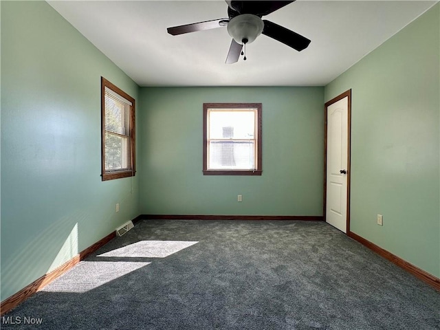 carpeted empty room with a wealth of natural light, visible vents, ceiling fan, and baseboards