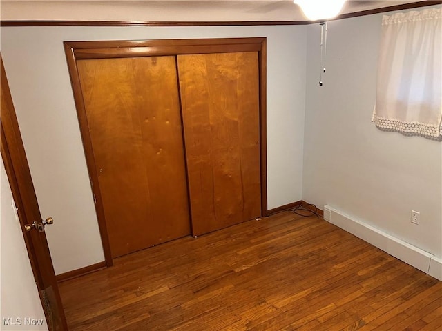 unfurnished bedroom with a closet, baseboards, and hardwood / wood-style floors