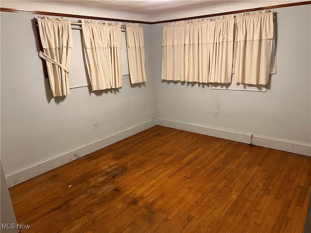 empty room with wood-type flooring and baseboards