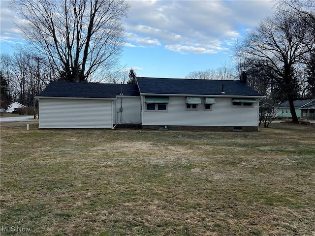 back of property with roof with shingles and a yard