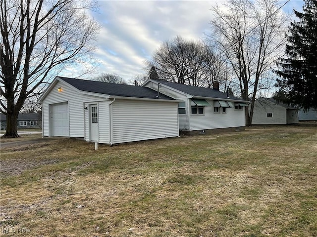 back of property featuring driveway, a chimney, and a lawn