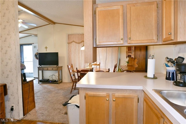 kitchen featuring wallpapered walls, a ceiling fan, lofted ceiling with beams, light countertops, and carpet flooring