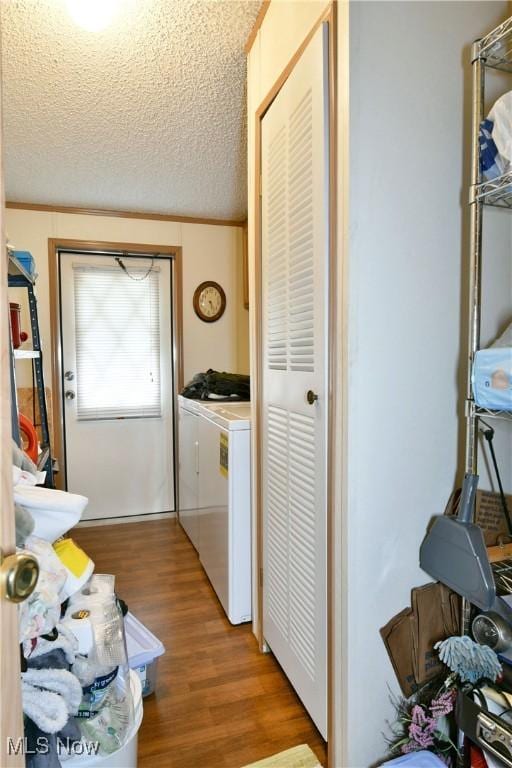 clothes washing area featuring laundry area, washing machine and dryer, a textured ceiling, and light wood-style floors