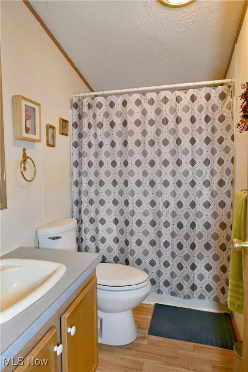 bathroom with a textured ceiling, toilet, a shower with shower curtain, wood finished floors, and vanity