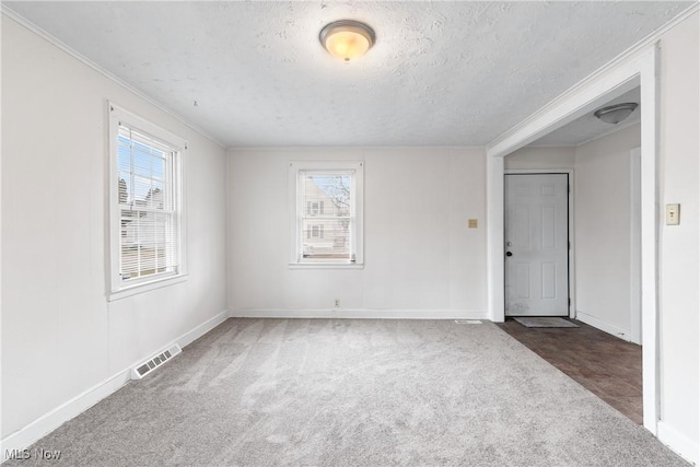 spare room featuring ornamental molding, visible vents, and carpet flooring