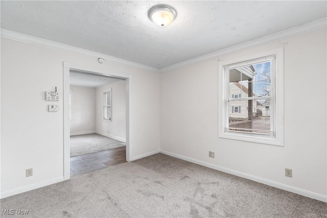 unfurnished room featuring carpet, crown molding, baseboards, and a textured ceiling