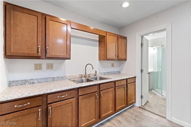 kitchen featuring light wood-style floors, brown cabinetry, a sink, and recessed lighting