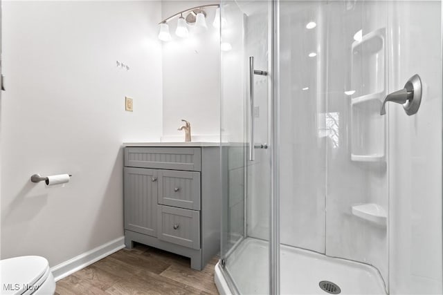 full bath featuring a stall shower, toilet, baseboards, and wood finished floors