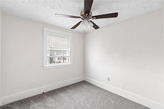 spare room with a textured ceiling, carpet floors, a ceiling fan, and baseboards