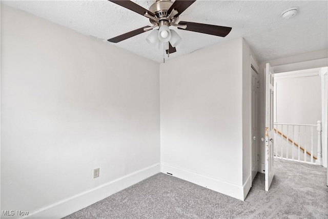 carpeted spare room featuring baseboards and a textured ceiling