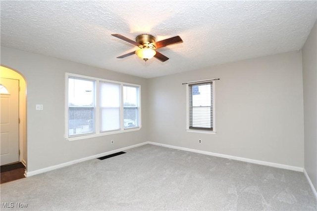 unfurnished room featuring visible vents, baseboards, ceiling fan, carpet, and a textured ceiling