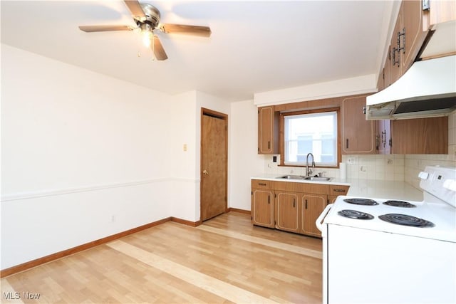 kitchen featuring light wood finished floors, electric stove, light countertops, under cabinet range hood, and a sink